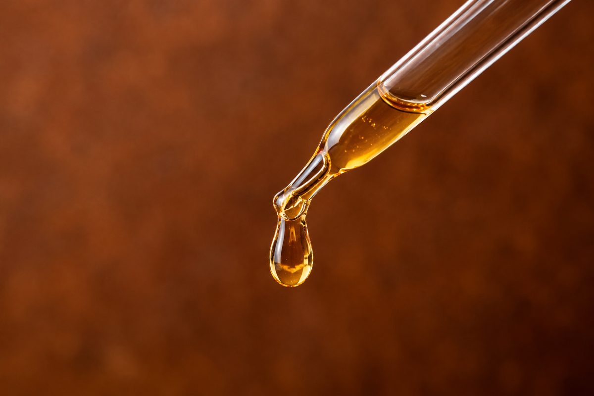 Active concentrated facial hydration serum droplet on a glass dropper pipette